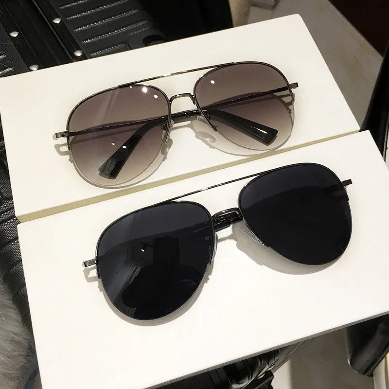 Ein Paar klassische Aviator-Sonnenbrille mit dunklen Gläsern und schwarzen Rahmen auf einer weißen Oberfläche.