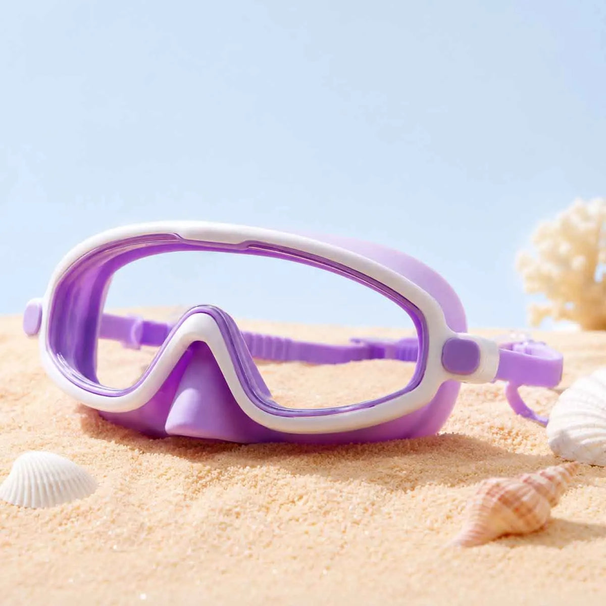 Lunettes de natation anti-buée violettes et blanches à large vue posées sur le sable avec des coquillages