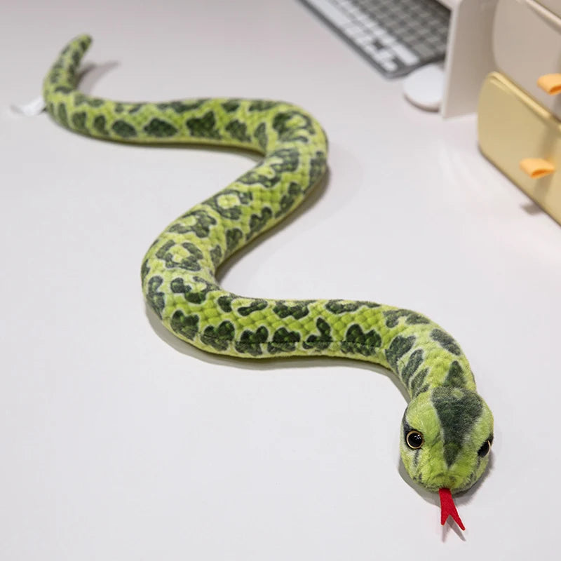A soft, realistic green anaconda plush toy snake lying on a white surface.