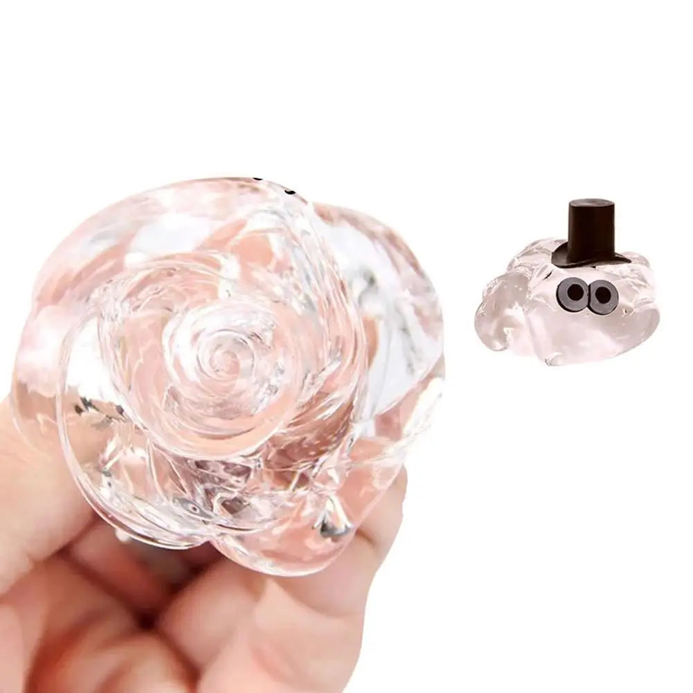 A clear crystal stress putty shaped like a rose is shown being held, next to its storage tin.