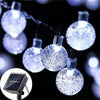 String lights featuring crystal balls powered by solar panels, illuminating a dark background.