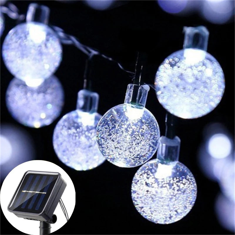 String lights featuring crystal balls powered by solar panels, illuminating a dark background.