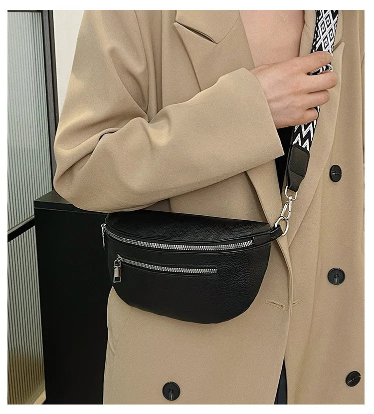 A close-up of a woman wearing a beige trench coat, holding a black multi-pocket PU leather waist bag with an adjustable strap
