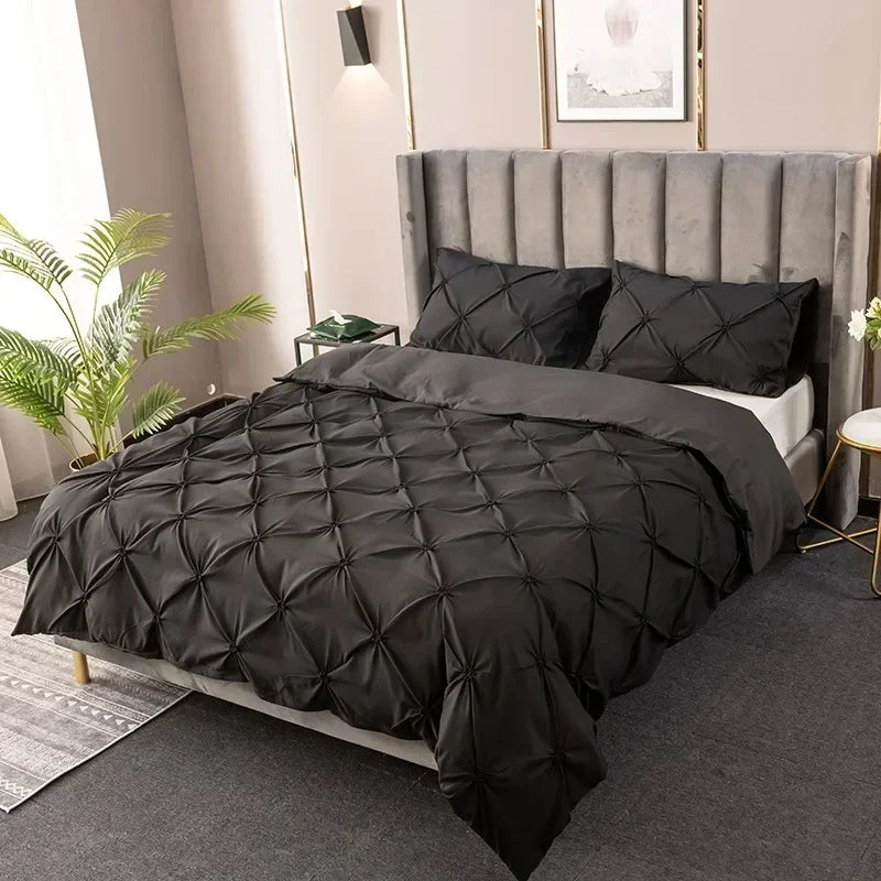 A black 3D pinch pleated duvet cover set displayed on a bed with a upholstered headboard.