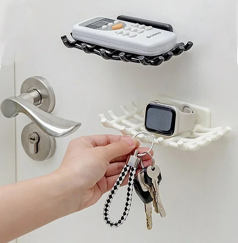 A hand is holding a set of keys and a small electronic device near a wall-mounted soap dish with drainage.