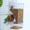 A transparent anti-spill parrot feeder with multiple compartments filled with seeds and pellets, mounted on a wire cage.