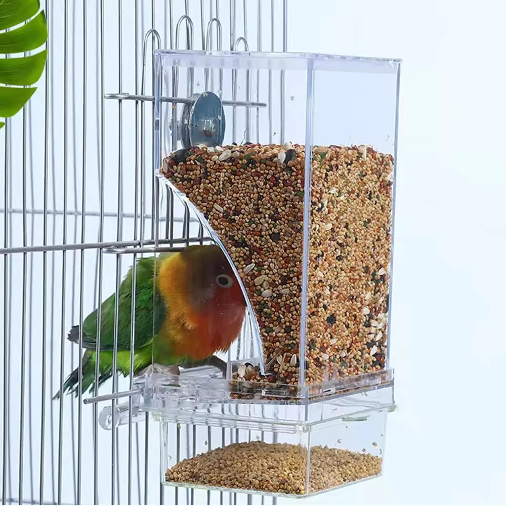 A transparent anti-spill parrot feeder with multiple compartments filled with seeds and pellets, mounted on a wire cage.