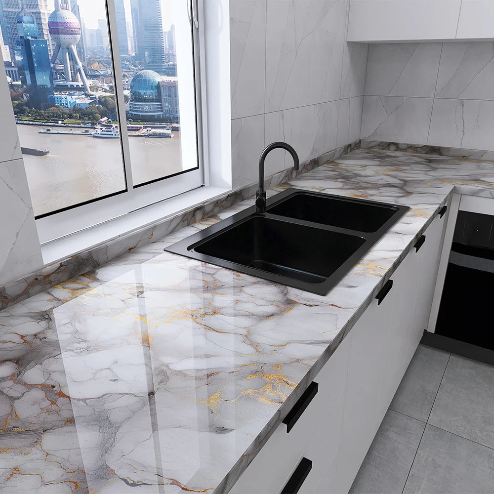 A modern kitchen countertop with a black sink set into a white cabinet featuring a marble effect surface.