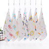 A set of five white muslin baby washcloths with colorful patterns hanging on a rack.
