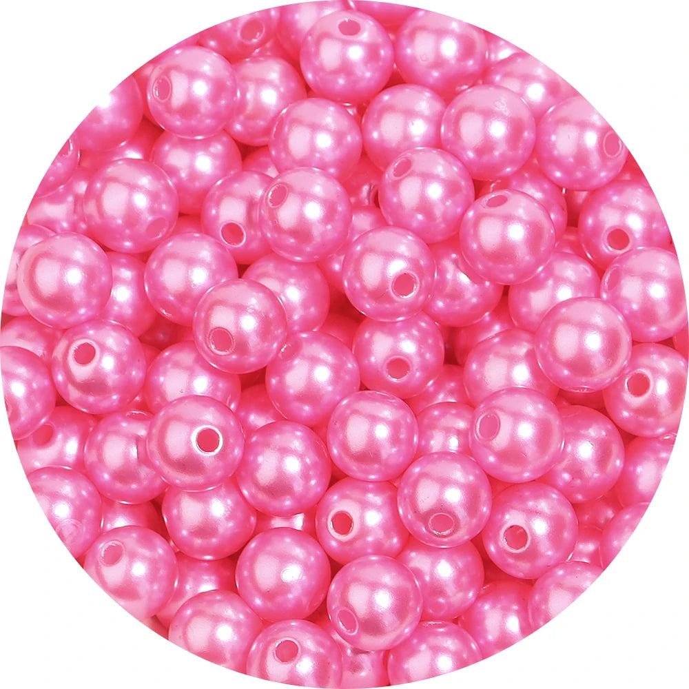 A close-up view of small, round pink imitation pearl beads for jewelry making.