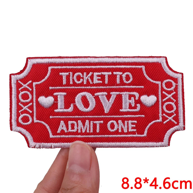 Red embroidered iron-on patch ticket to love admit one design being held by a hand