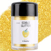 A glass jar of edible gold glitter powder with a white label set against a background of gold glitter.