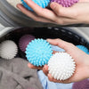 Hands holding reusable laundry balls in various colors including blue, purple, and white.