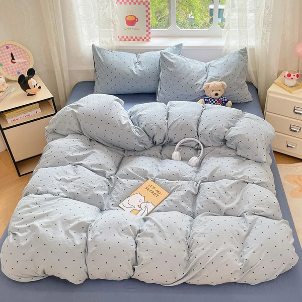 A light blue quilted duvet cover set with matching pillowcases and a teddy bear toy on a bed.