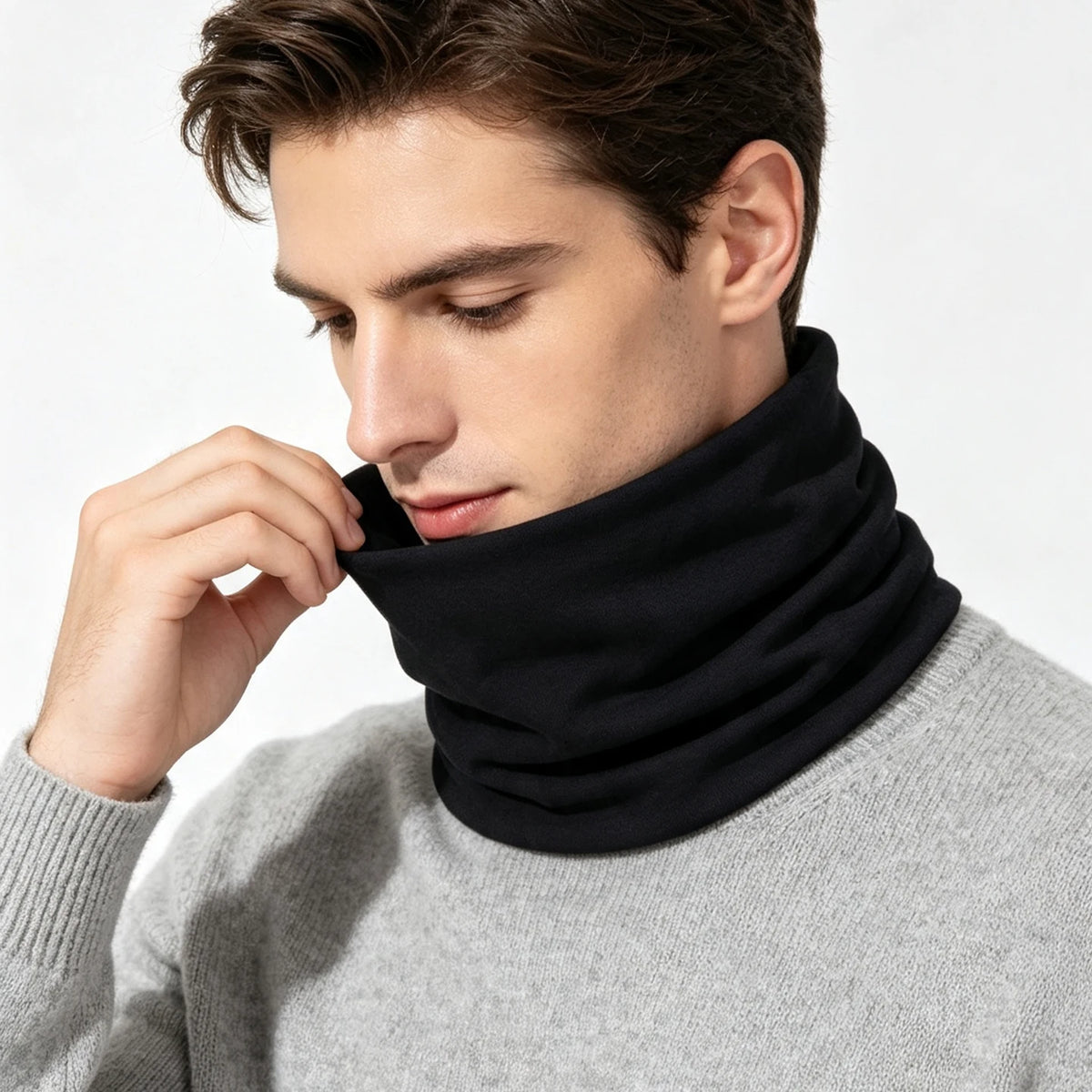 A man wearing a black neck warmer scarf over a gray sweater.