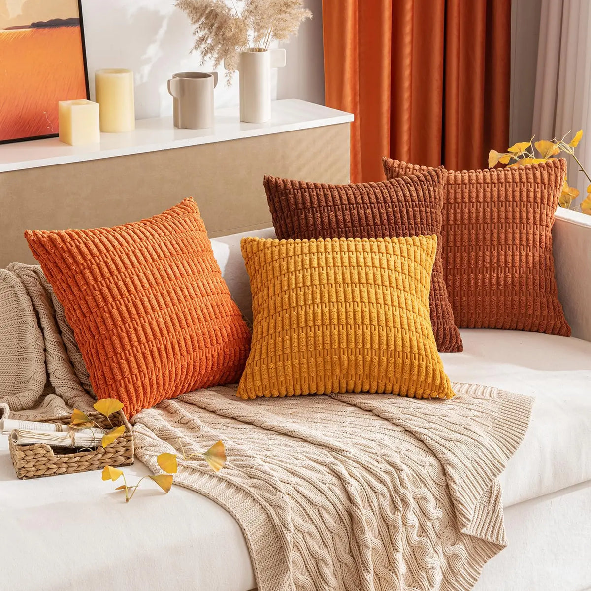 A set of three textured corduroy throw pillow covers in shades of orange, mustard yellow, and rust on a light sofa.