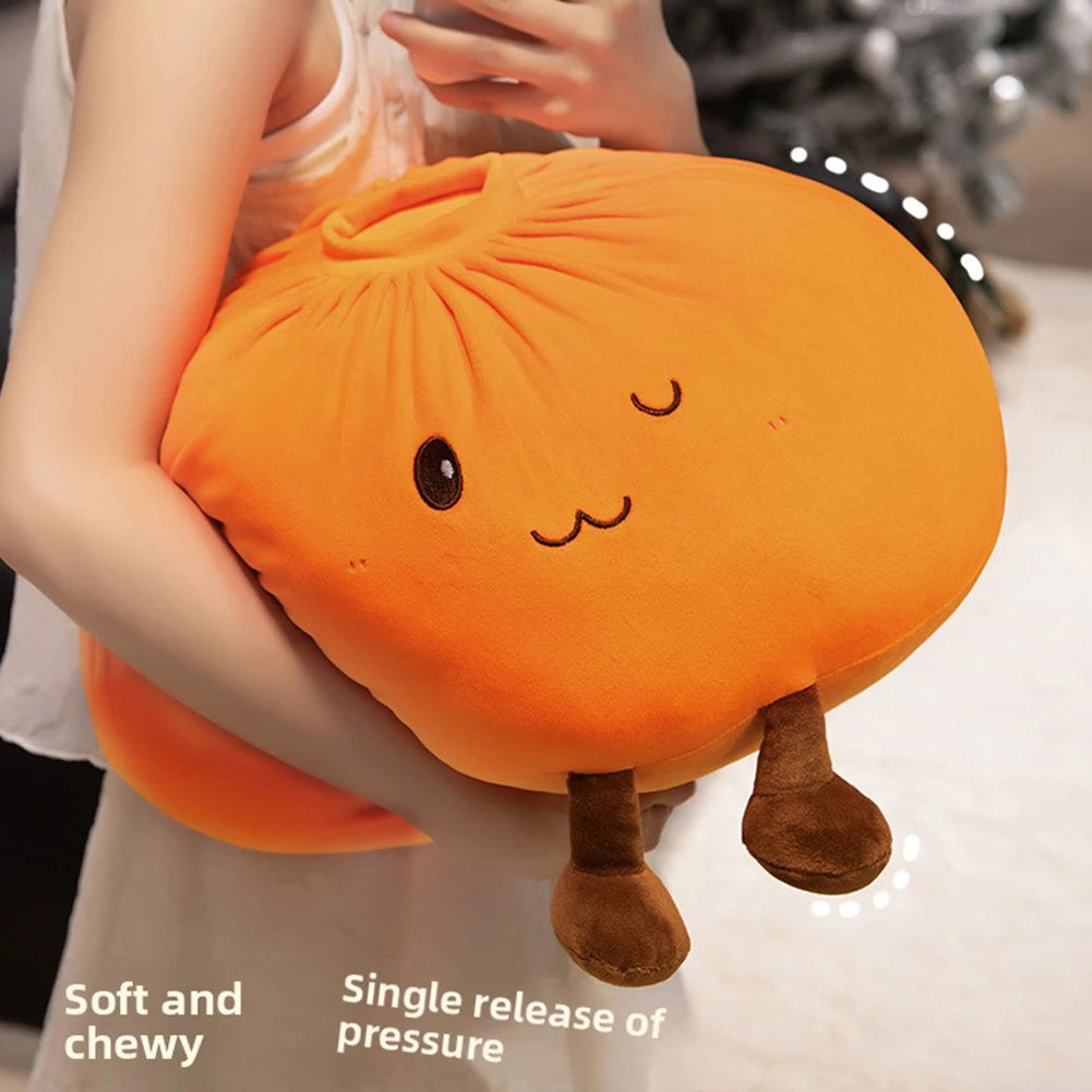Un coussin en peluche de dumpling orange avec de petites oreilles et des pieds doux, à côté d'une main.