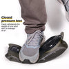 A close-up of a gray hiking shoe and a black collapsible hydration bladder being shown for a pressure test.