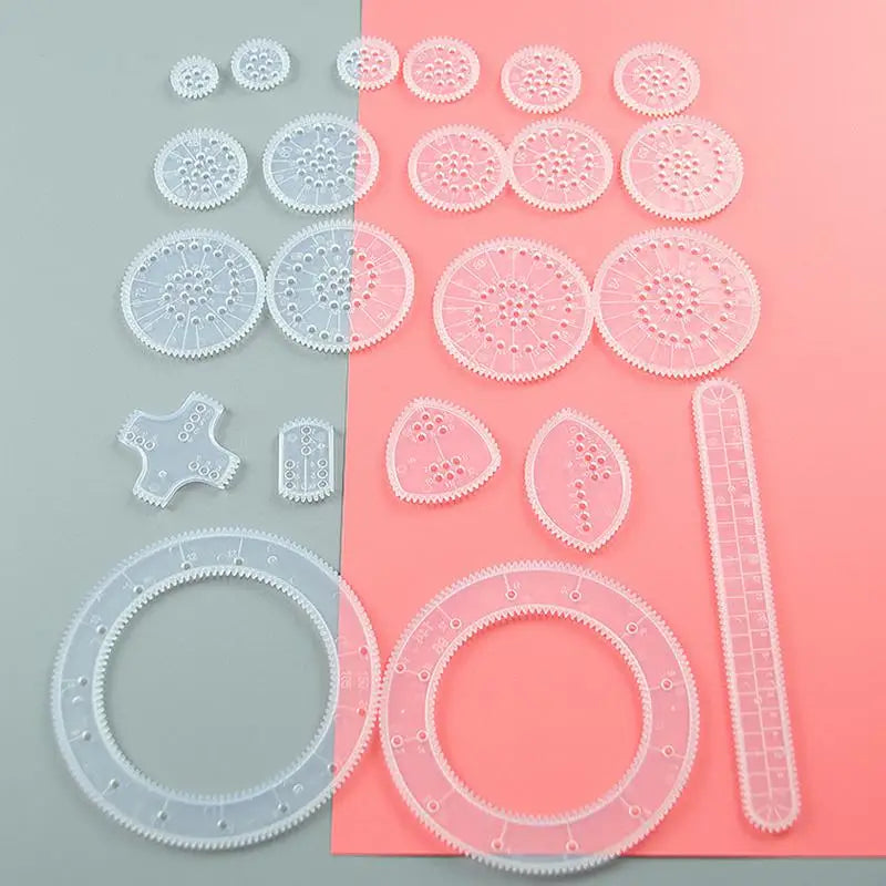 A collection of 22 clear plastic spirograph drawing pieces in various sizes and shapes arranged on a pink background.