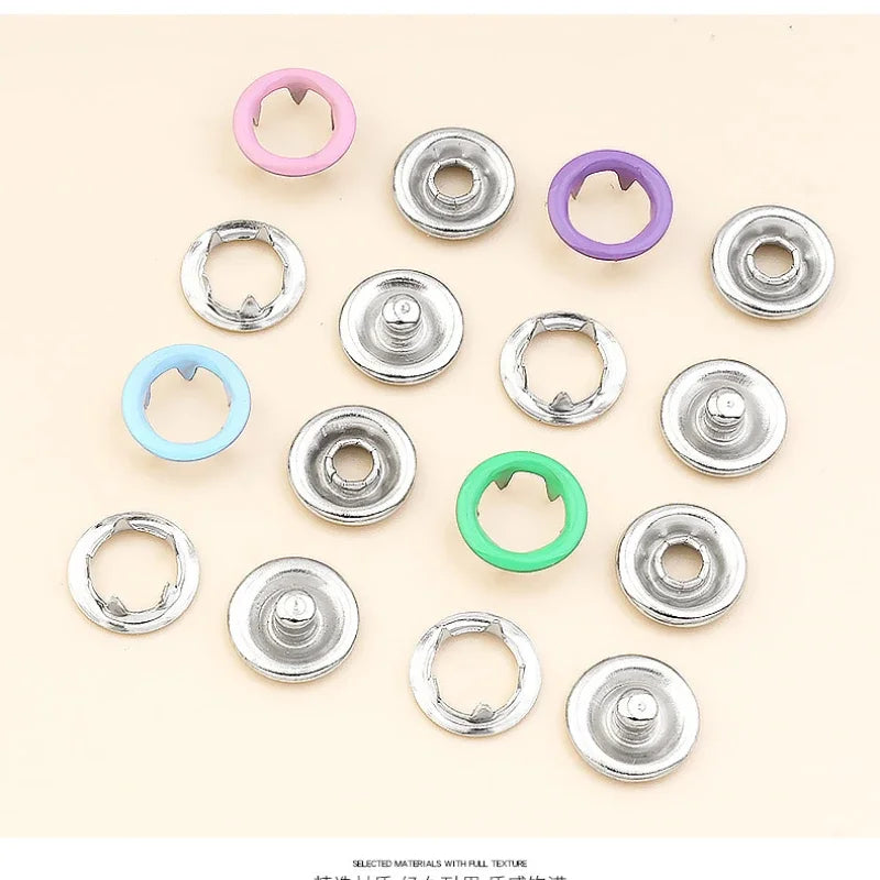 Colección de hebillas y pinzas metálicas con garras plateadas y moradas para ropa y bolsos.