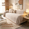 A beige fishbone pattern anti-slip sofa cover draped over a light-colored sofa in a bright living room.