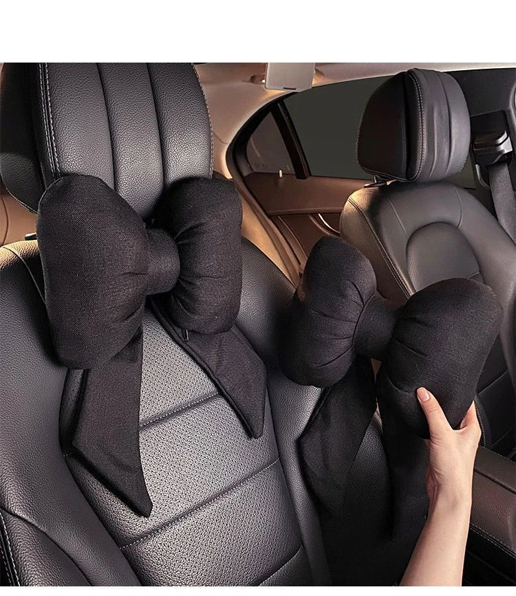 Black butterfly bow tie neck pillow with a black fabric cover shown in a car seat interior.