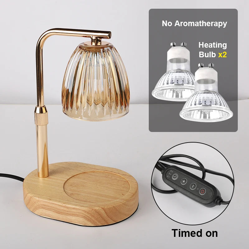 A brass-colored candle warmer lamp with a glass shade sits on a wooden base, shown alongside heating bulbs and a timer switch