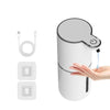 A white touchless automatic soap dispenser with a pump mechanism and charging components shown next to a hand.
