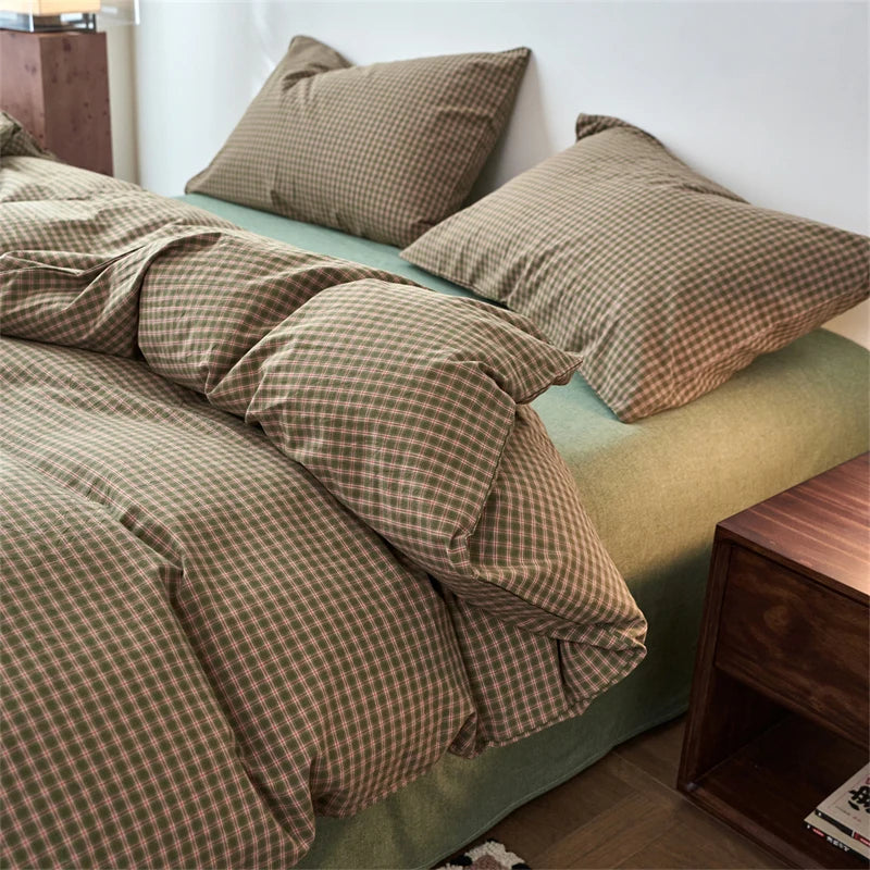 A plaid duvet cover in olive green and brown tones with matching pillows on a bed.