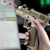 A hand holds a tan toy blaster, aiming it at a target with visible projectiles.