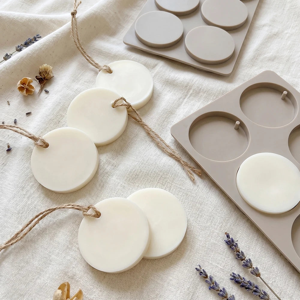 A collection of white silicone discs for hanging soap and aromatherapy, displayed on a linen fabric.