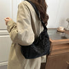 A person holds a black leopard print crossbody bag against a light beige coat.