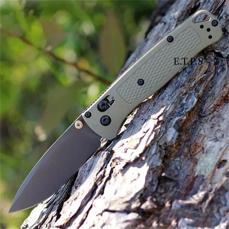 A folding pocket knife with a drop point blade is shown resting on a tree trunk.