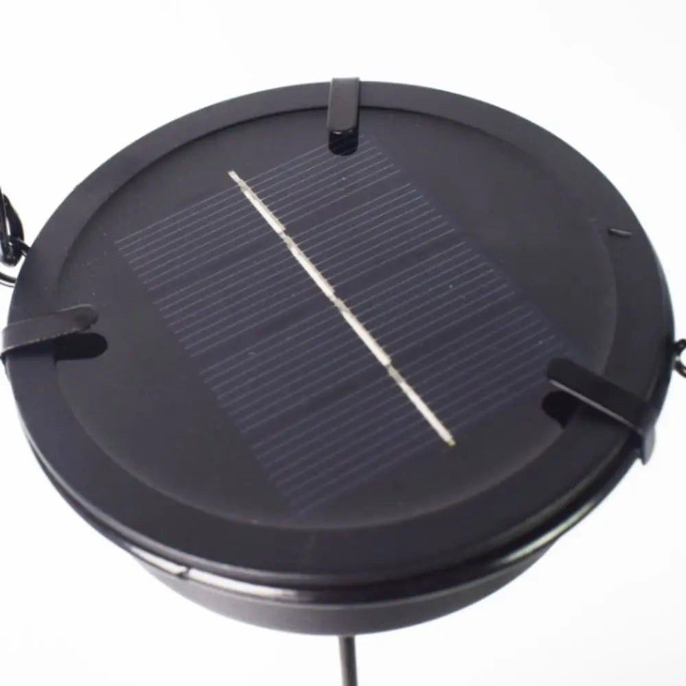 A black solar hollow-out lantern with a glass panel showing a light beam.