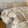 A beige and yellow floral printed duvet cover set with matching pillowcases on a bed.