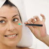A woman holds a small, light blue ear cleaning tip against her ear while a white towel is visible.