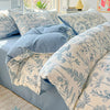A set of floral duvet cover, flat sheet, and pillowcases in blue and white patterns on a bed.