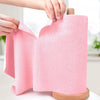 A hand is pulling a pink reusable microfiber cleaning cloth from a wooden roller.