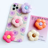 A pink and purple patterned foldable phone grip stand featuring flower-shaped silicone grips in various pastel colors.