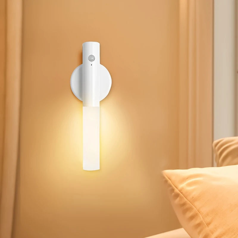 A white magnetic LED wall light with a motion sensor mounted on a beige wall.