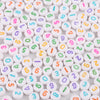 A close-up view of numerous white acrylic letter beads in various colors and shapes, arranged randomly.