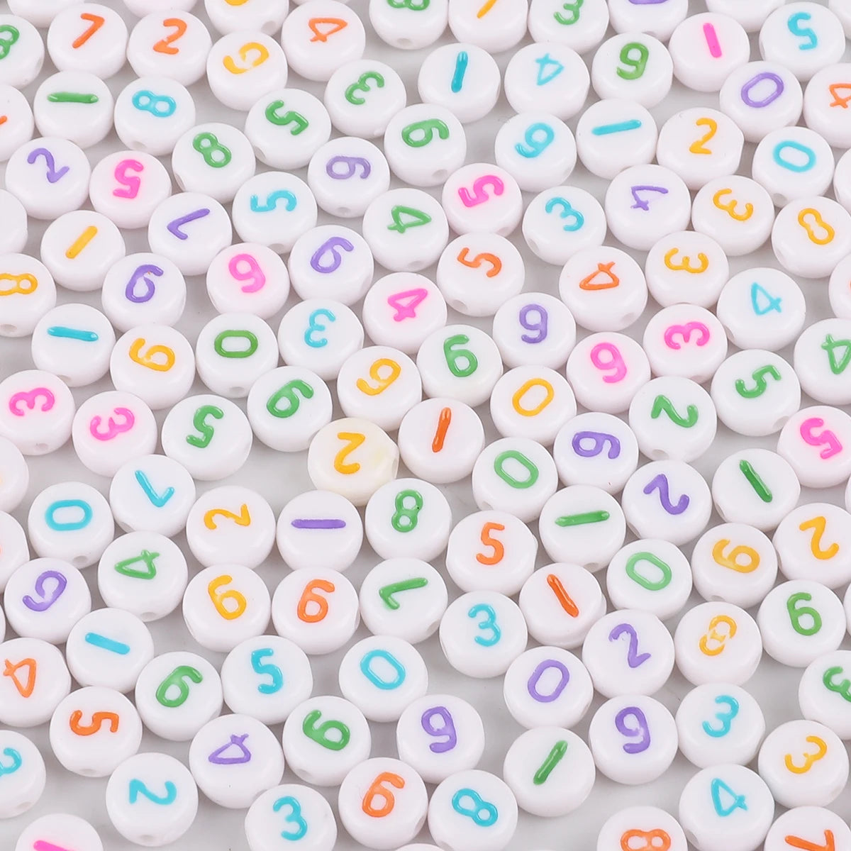 A close-up view of numerous white acrylic letter beads in various colors and shapes, arranged randomly.