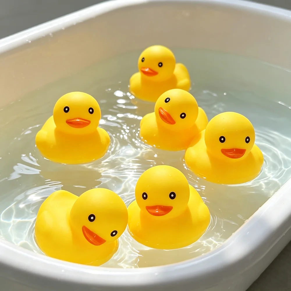 Five bright yellow rubber ducklings floating in clear water in a white dish.