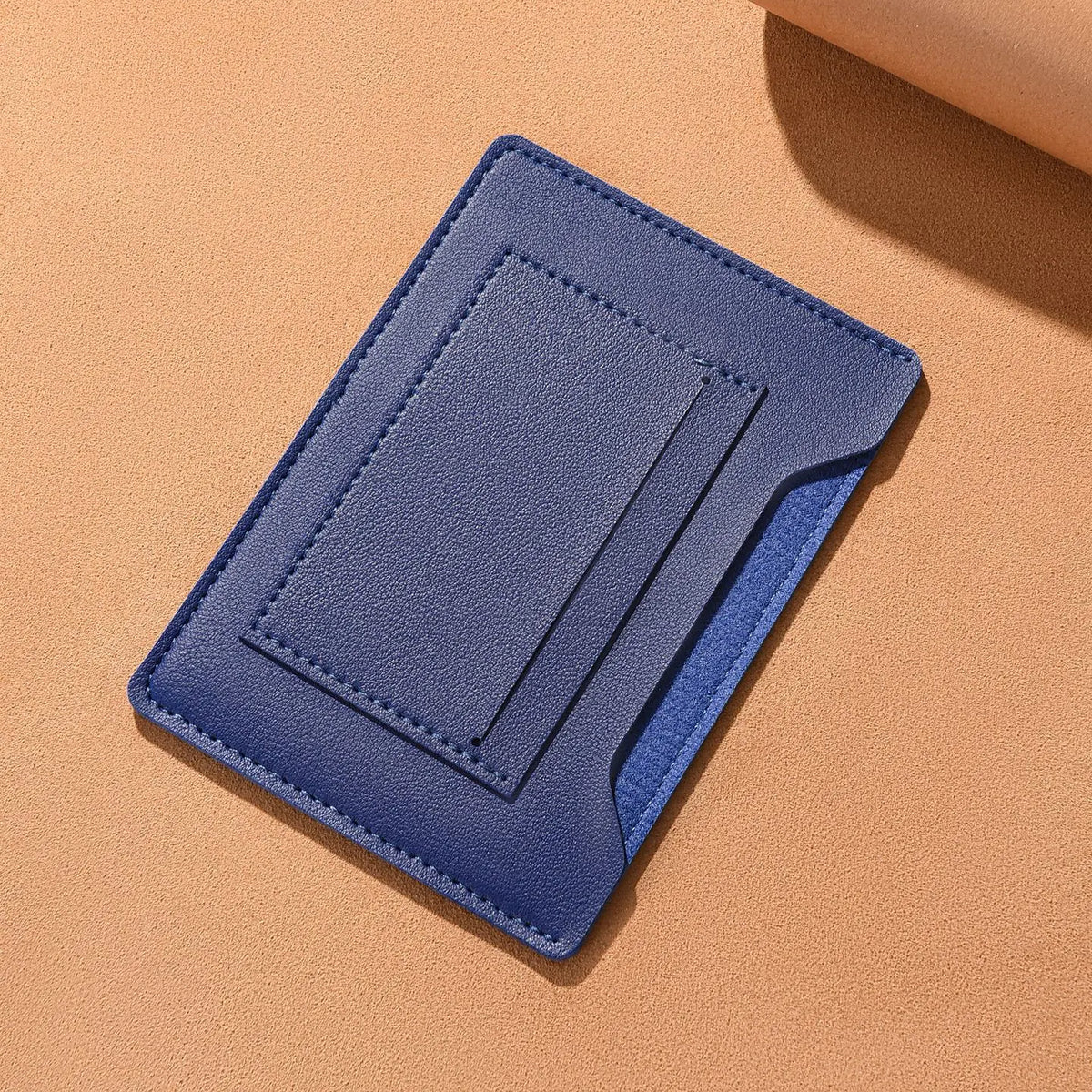 A dark blue ultra-thin passport holder with card slots resting on a light orange background.