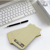 A set of kraft paper cash envelopes is shown next to a white keyboard and a black pen on a white desk.