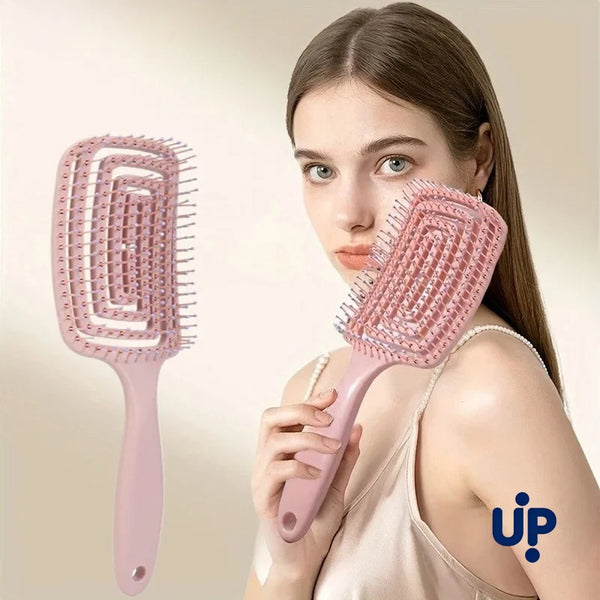 A woman holds a pink volumizing detangling hair comb, showing its design and size.
