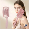 A woman holds a pink volumizing detangling hair comb, showing its design and size.