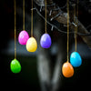 A collection of colorful plastic Easter eggs in various shades including pink, yellow, purple, green, and orange hanging from