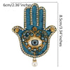A handprint design featuring blue fabric, gold accents, and a central eye made of sparkling beads and rhinestones.