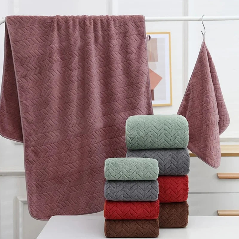 A stack of soft, textured bath towels in shades of pink, green, and gray on a white surface.